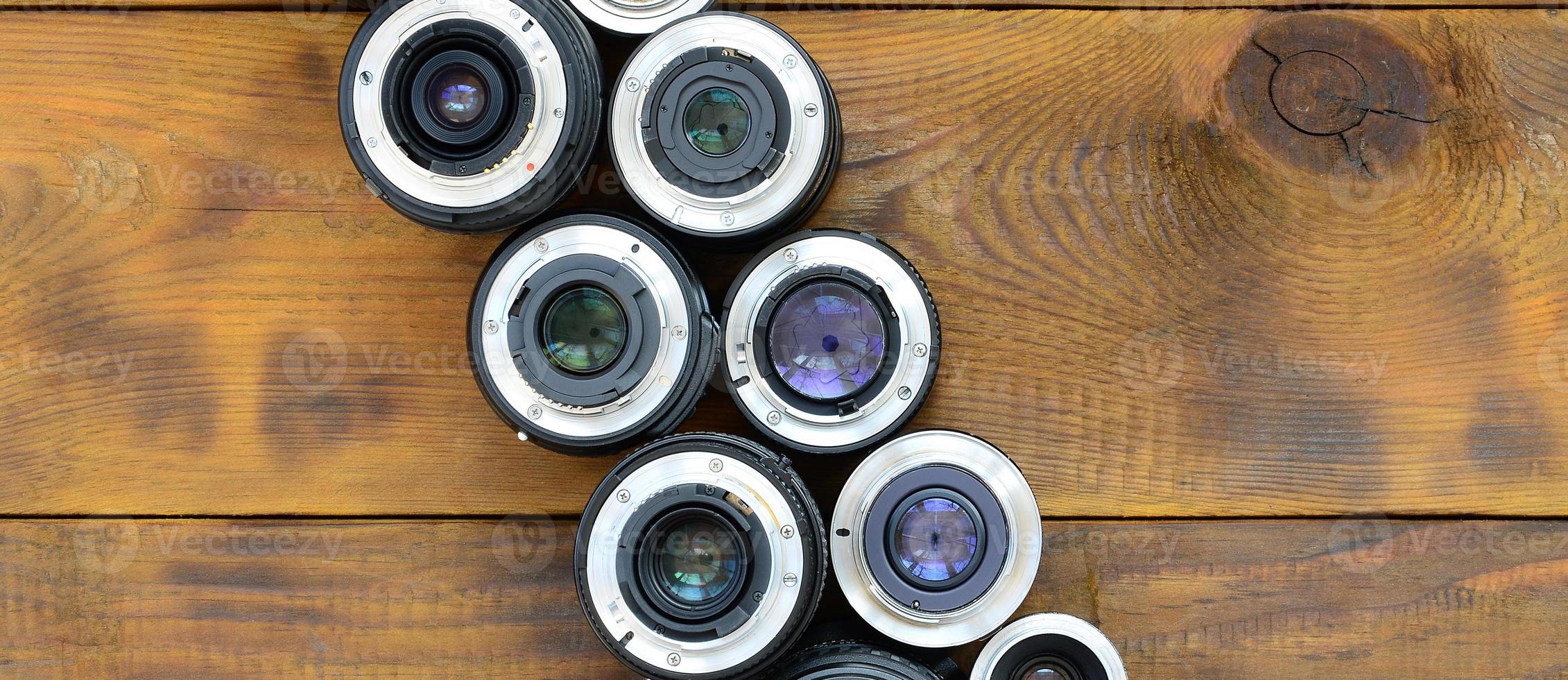 várias lentes fotográficas estão em um fundo de madeira marrom. espaço para texto foto