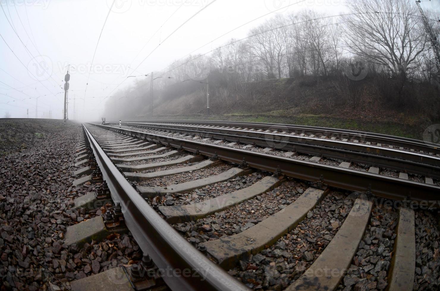 a ferrovia em uma manhã nublada. muitos trilhos e dormentes vão para o horizonte enevoado. foto olho de peixe com distorção aumentada