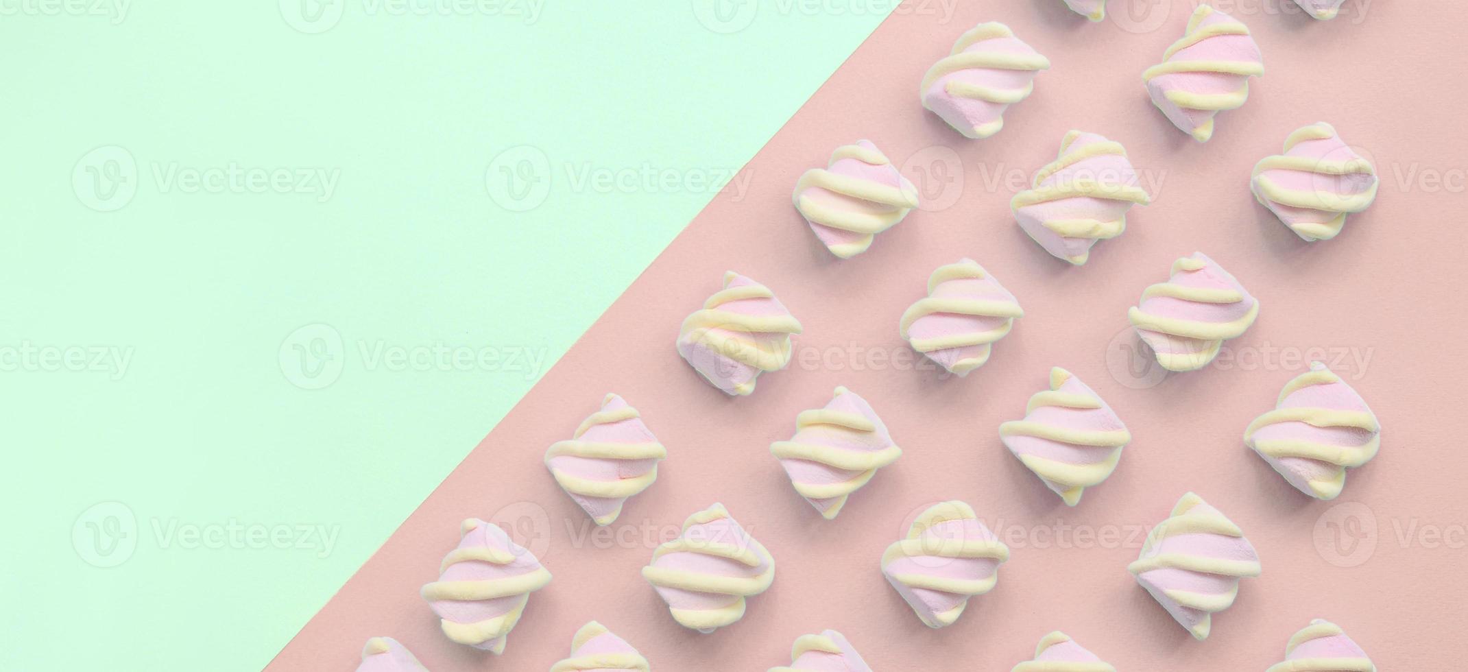 marshmallow colorido disposto em fundo de papel turquesa e rosa foto