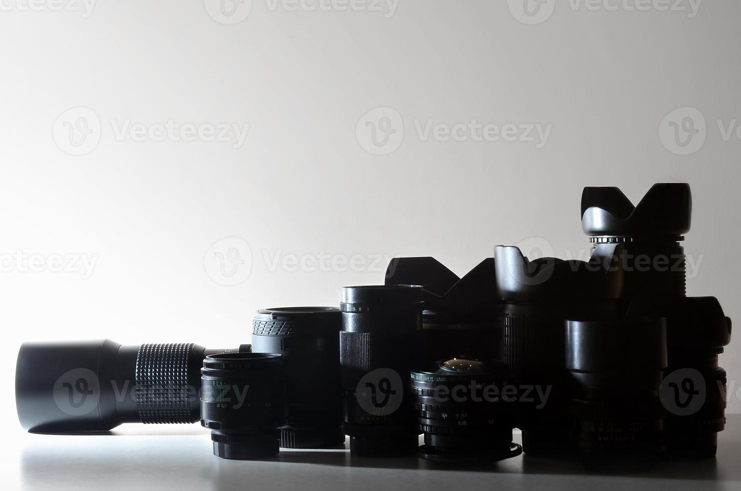 muitas lentes profissionais diferentes para câmera slr estão em uma mesa incolor foto