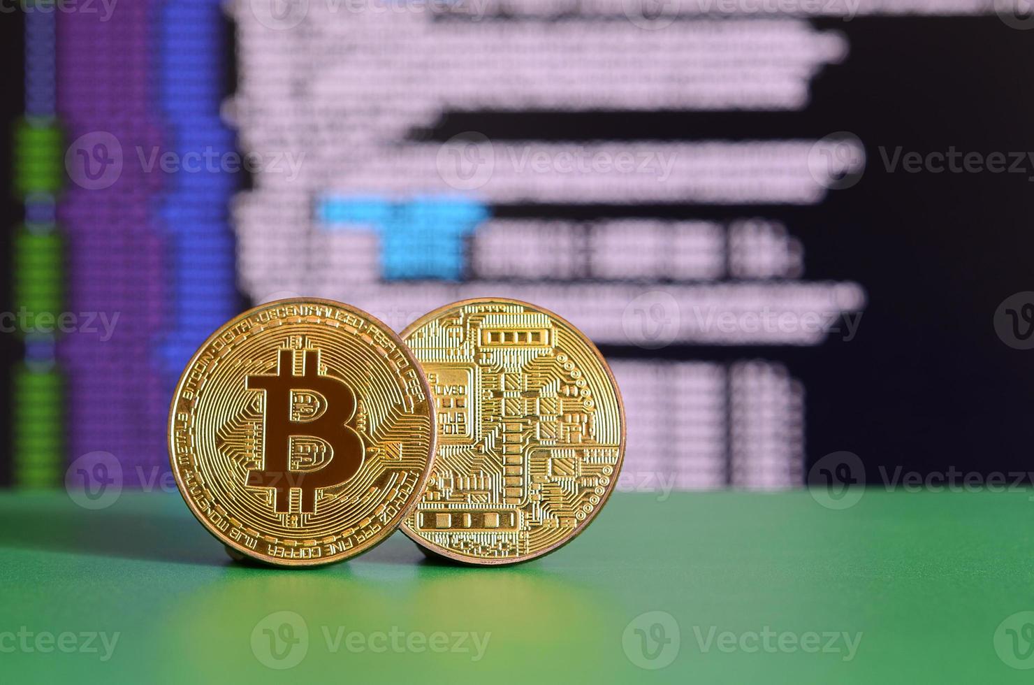 dois bitcoins de ouro estão na superfície verde no fundo da tela, que mostra o processo de mineração da moeda criptográfica foto