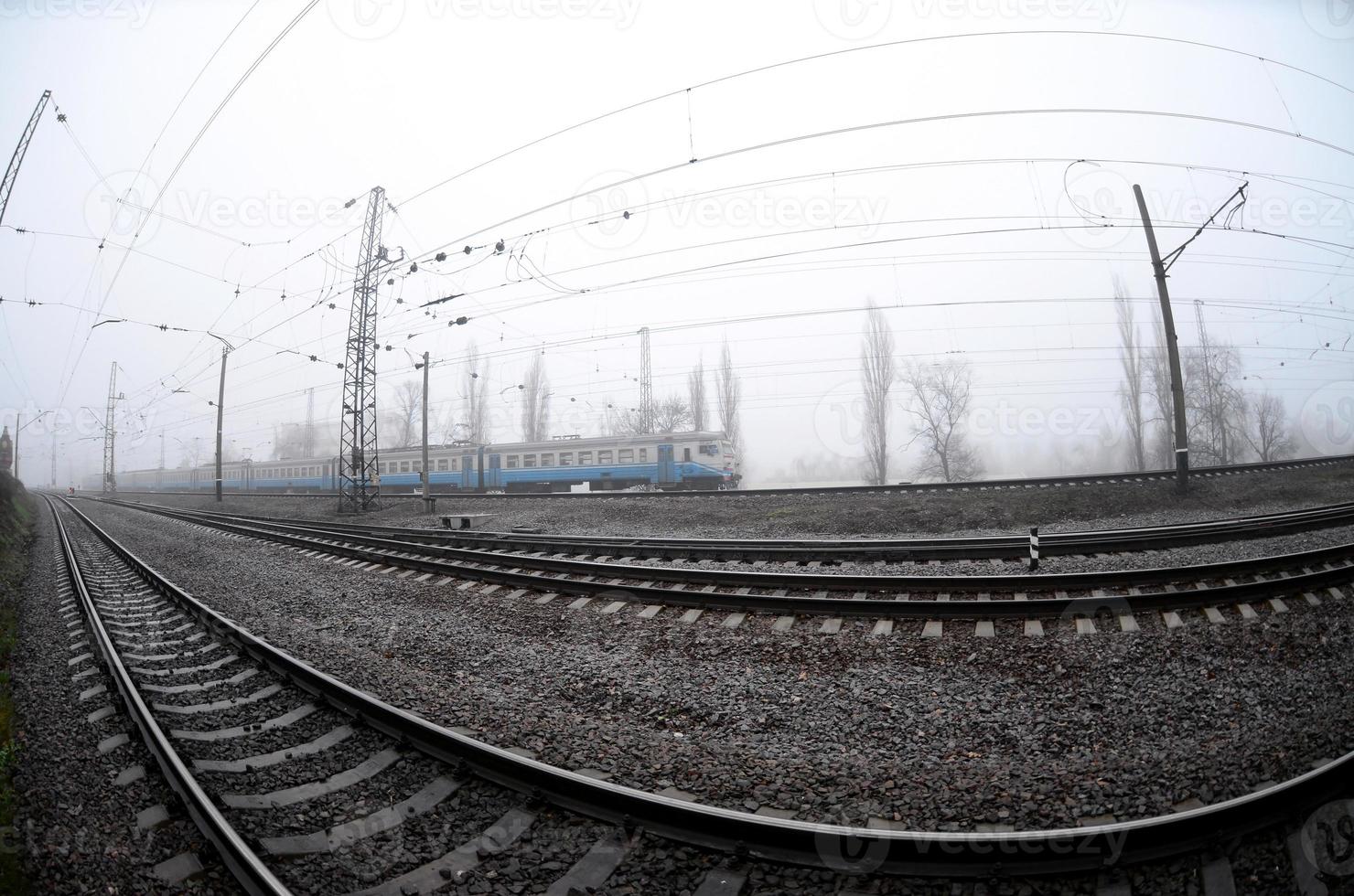 o trem suburbano ucraniano corre ao longo da ferrovia em uma manhã nublada. foto olho de peixe com distorção aumentada