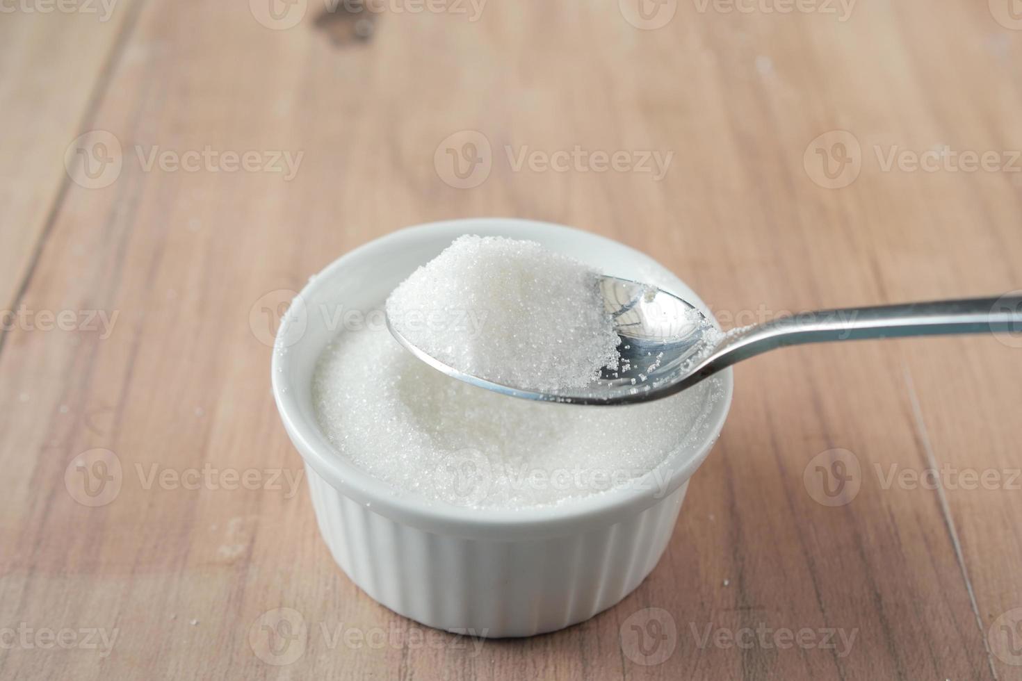 açúcar branco e colher em um recipiente com fundo preto, foto
