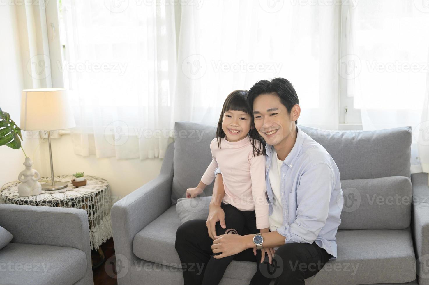 retrato de pai asiático e filha sentada no sofá na sala de estar foto