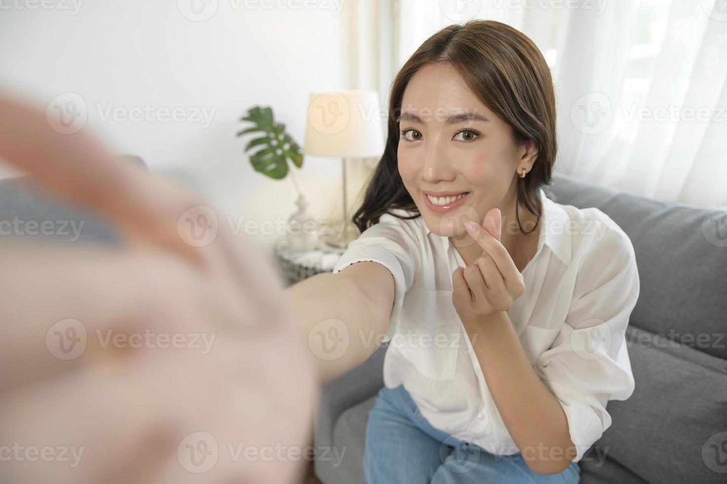 jovem mulher asiática fazendo videochamada no sofá na sala de estar foto