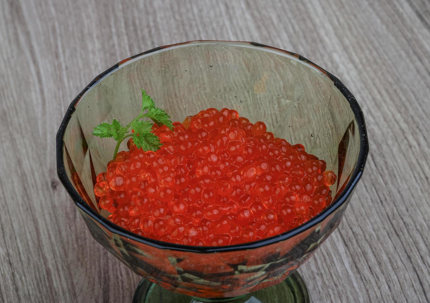 caviar vermelho em uma tigela sobre fundo de madeira foto