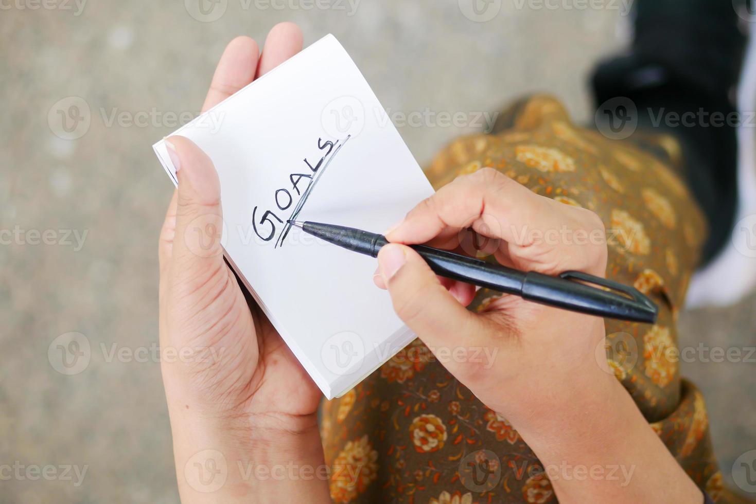mão de mulheres escrevendo metas de ano novo no bloco de notas foto