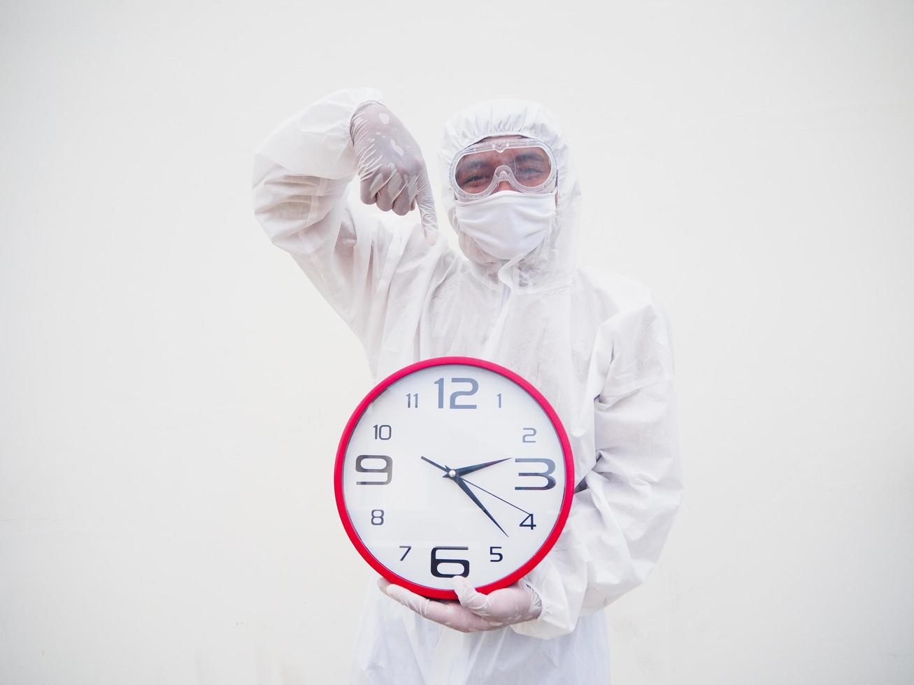 retrato de médico ou cientista em uniforme de suíte de ppe segurando o despertador vermelho e olhando para a câmera em vários gestos. fundo branco isolado conceito covid-19 foto