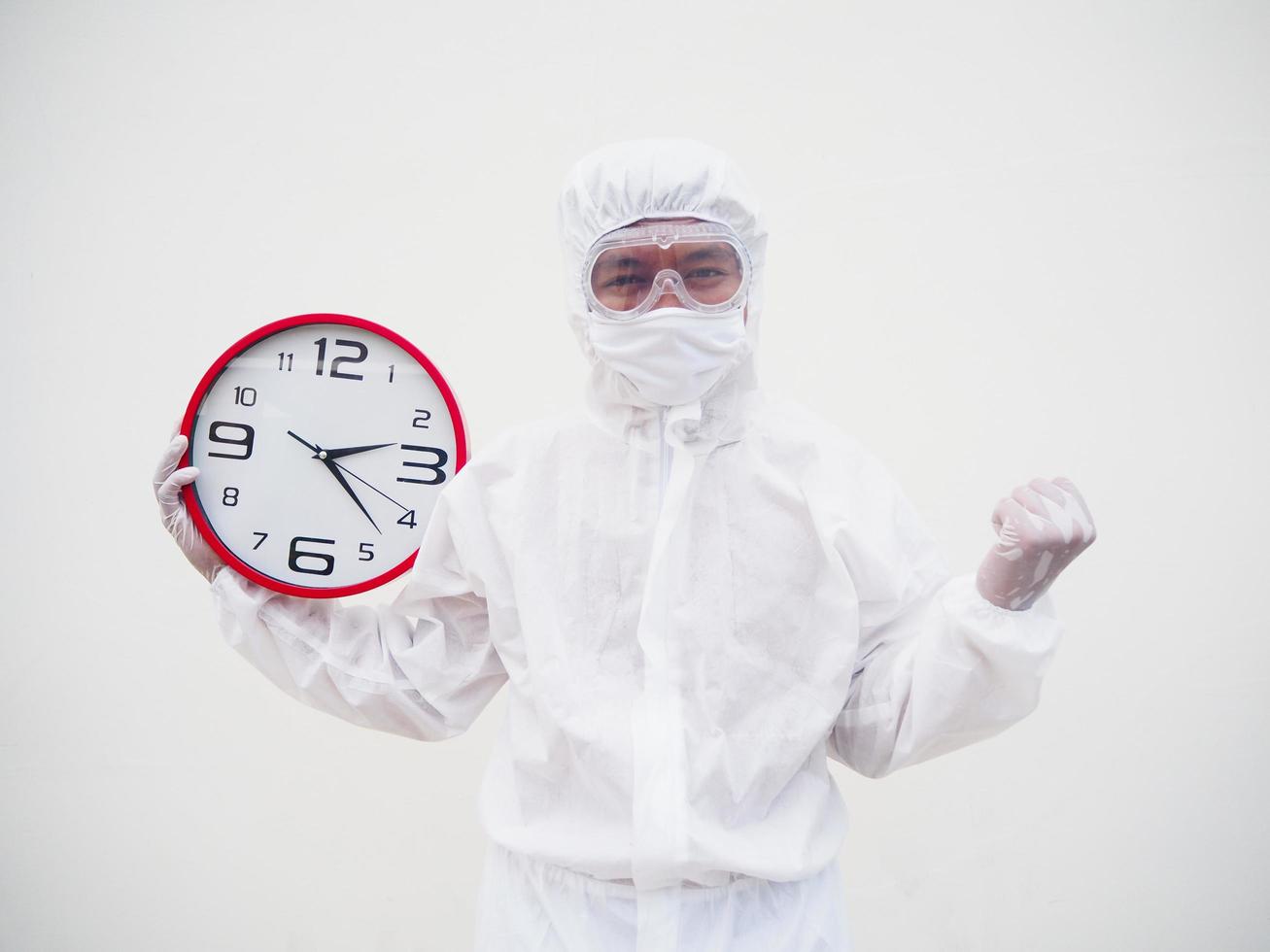 retrato de médico ou cientista em uniforme de suíte de ppe segurando o despertador vermelho e olhando para a câmera em vários gestos. fundo branco isolado conceito covid-19 foto