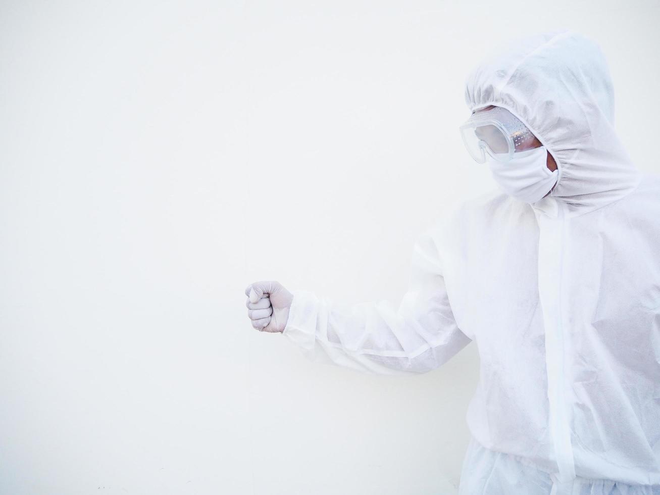 médico asiático ou cientista em uniforme de conjunto de EPI mostrando o punho cerrado para acertar algo para texto ou design em um fundo branco. conceito de coronavírus ou covid-19 foto