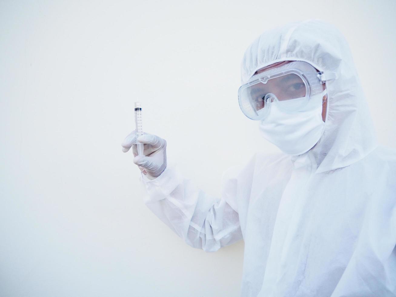médico asiático ou cientista em uniforme de conjunto de EPI segurando a seringa de injeção médica. coronavírus ou covid-19 conceito isolado fundo branco foto
