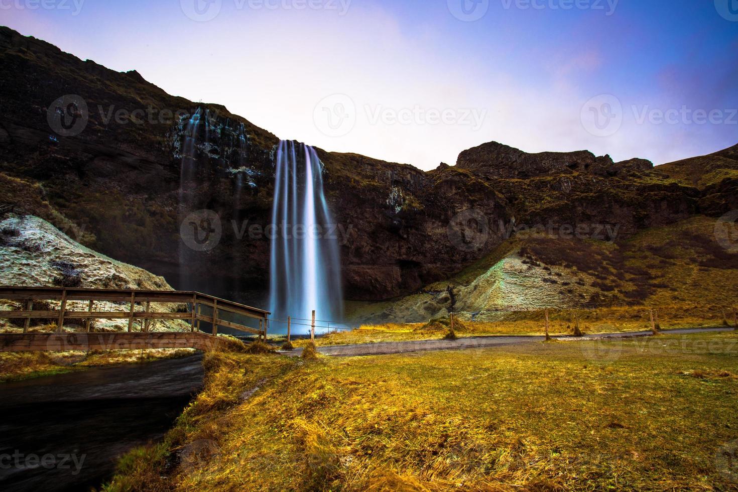 seljalandsfoss, uma cachoeira com uma pequena caverna atrás dela na região sul da islândia, faz parte do rio seljalands que tem sua origem na geleira do vulcão eyjafjallajokull foto