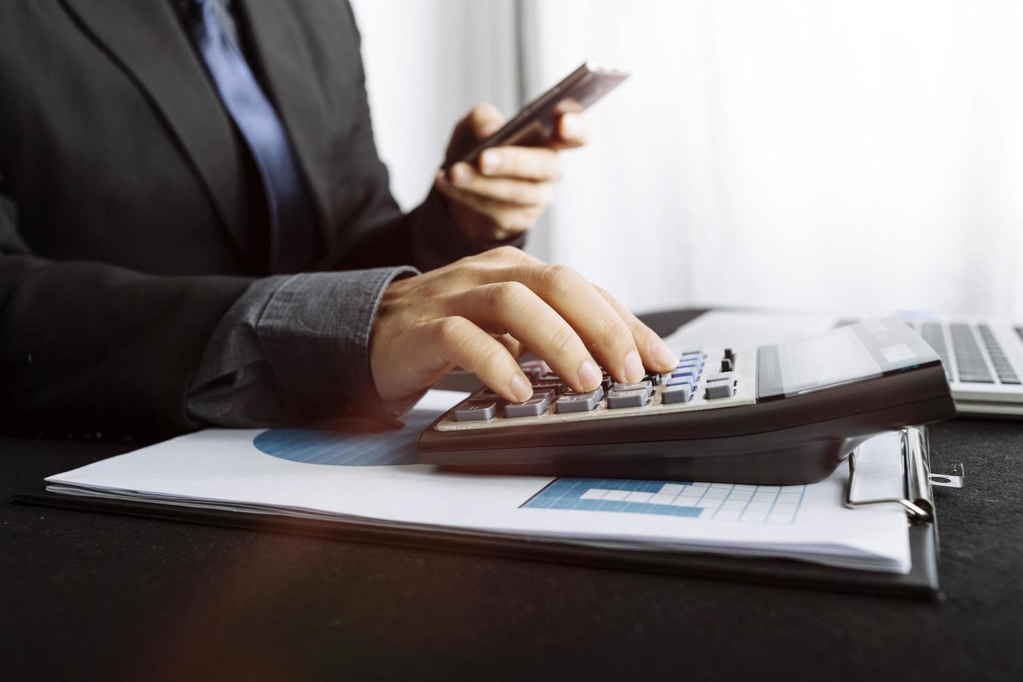 mulher empreendedora usando uma calculadora com uma caneta na mão, calculando despesas financeiras em home office foto