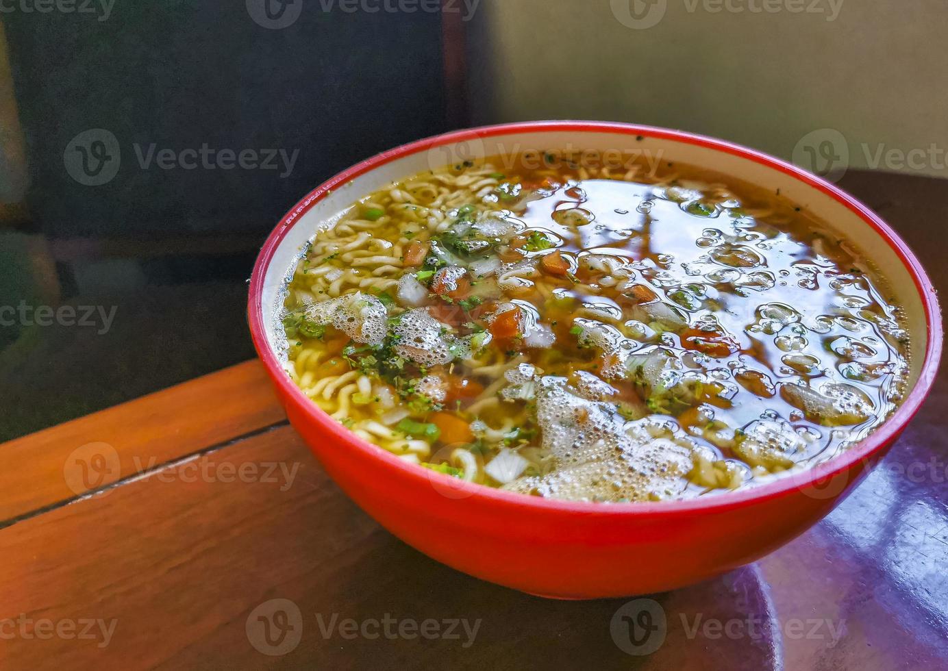 sopa instantânea de macarrão em tigela rosa na mesa de madeira marrom. foto