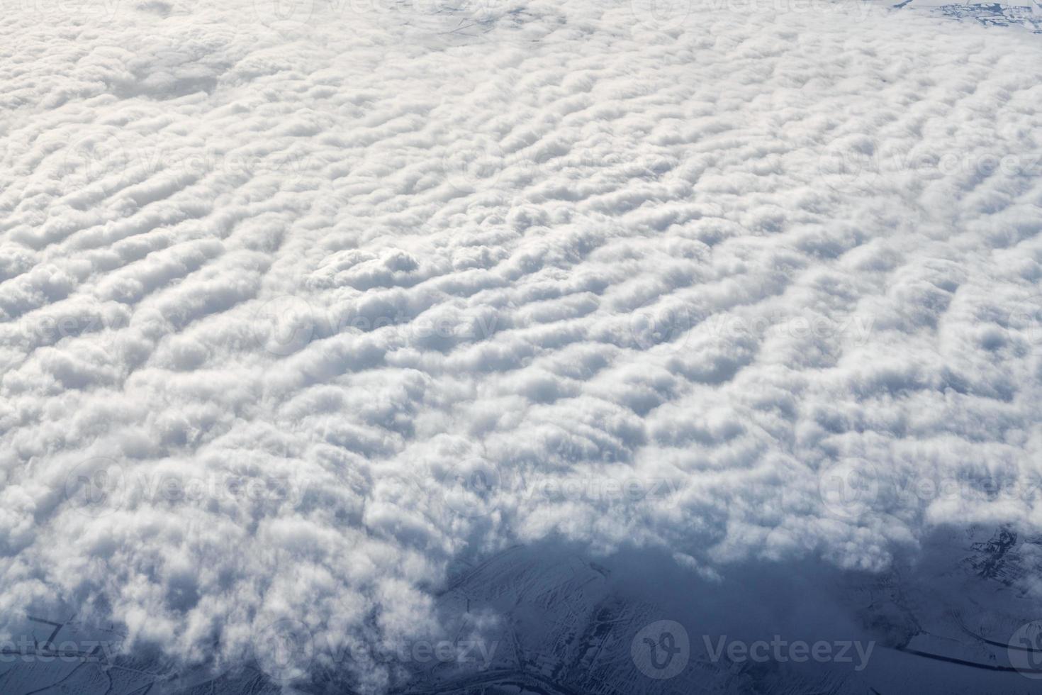sobre nuvens vista superior da janela da aeronave, grossas nuvens azuis brancas parecem espuma macia foto