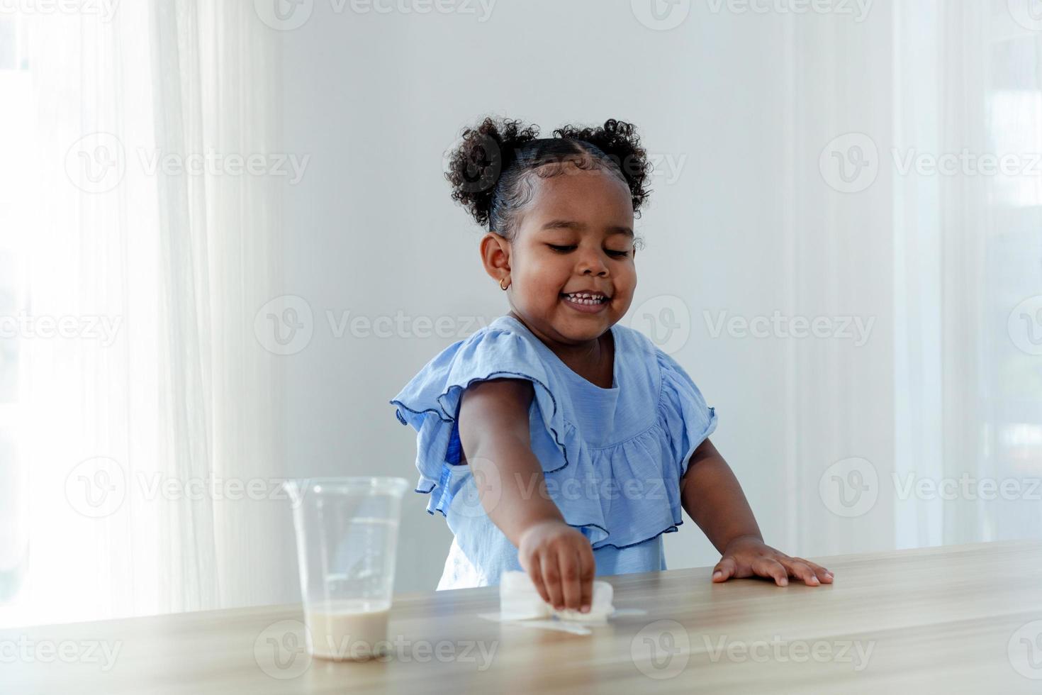 uma menina bonitinha gosta de limpar o leite derramado na mesa. foto