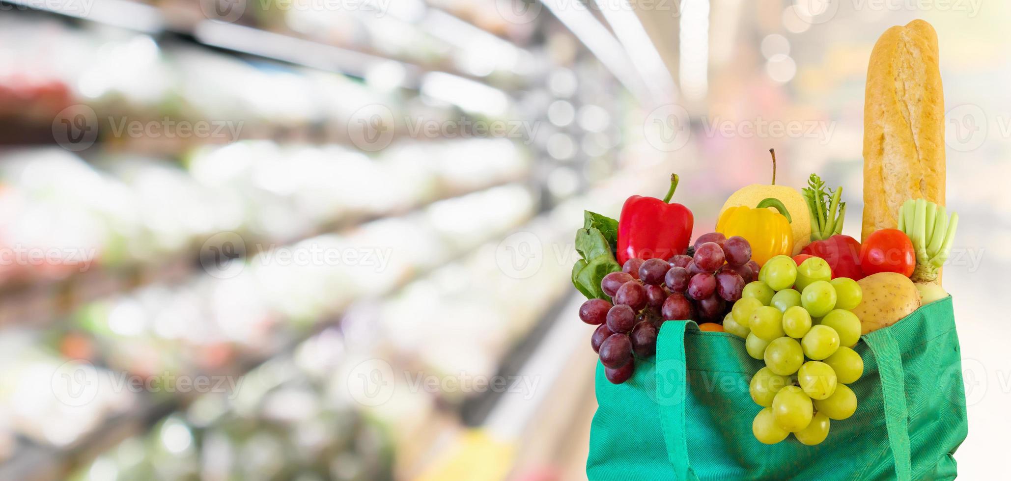 frutas e legumes frescos em sacola de compras verde reutilizável com supermercado desfocado fundo desfocado com luz bokeh foto