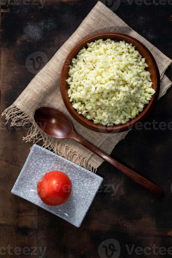 tigela de couve-flor tem tomate na mesa de madeira. foto