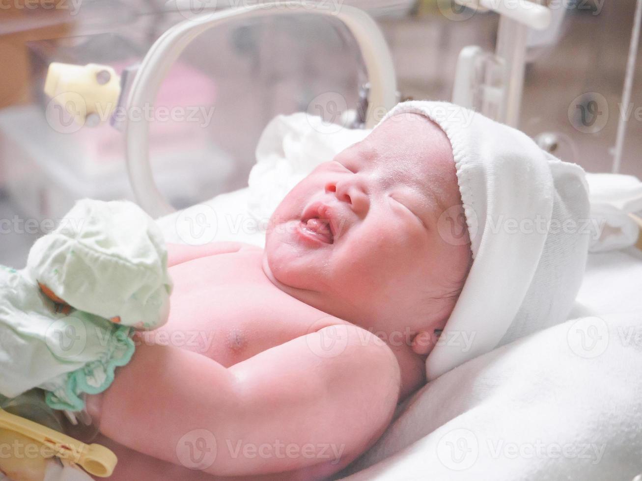 menina recém-nascida dentro da incubadora na sala de parto do hospital foto