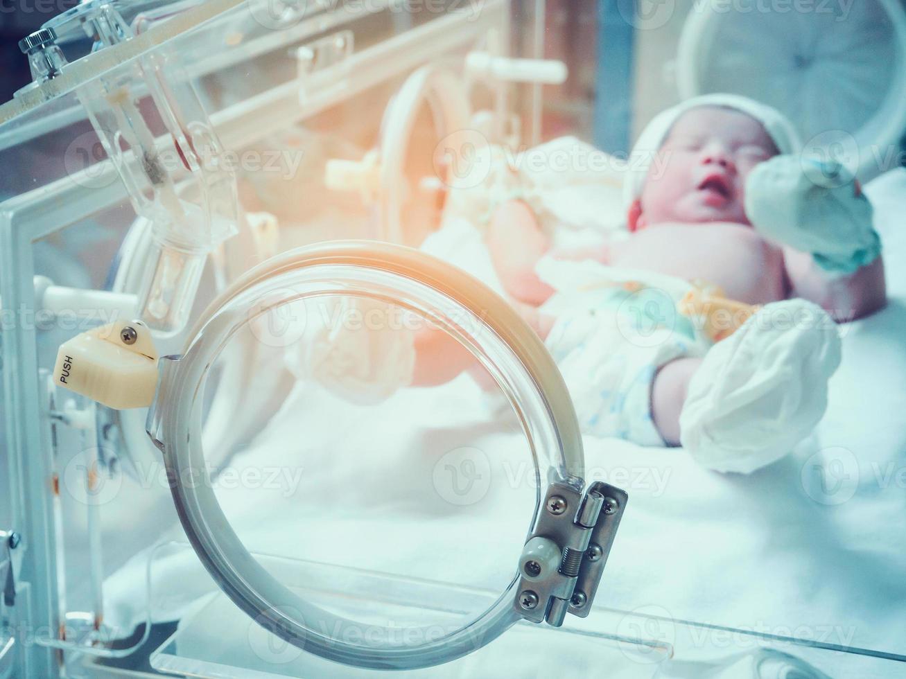 menina recém-nascida dentro da incubadora na sala de parto do hospital foto