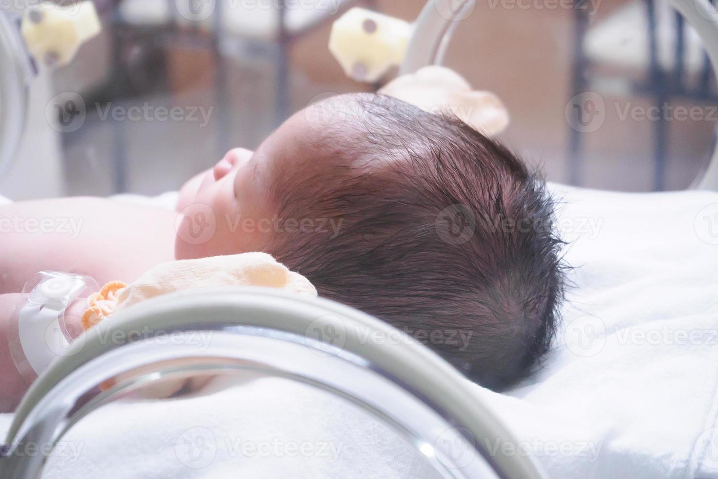 menina recém-nascida dentro da incubadora na sala de parto do hospital foto