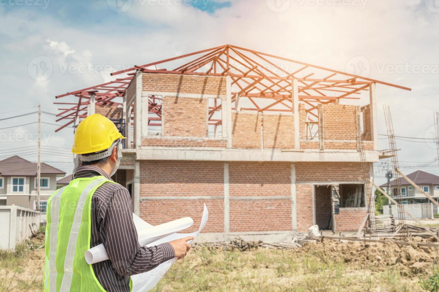 trabalhador arquiteto engenheiro profissional com capacete protetor e papel de plantas no canteiro de obras de construção de casas foto