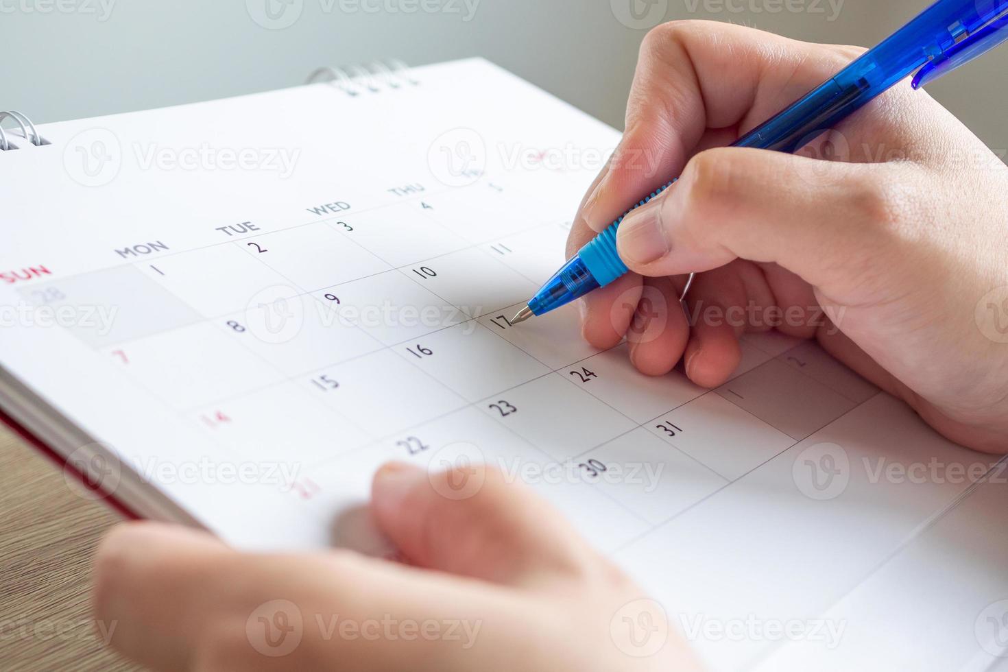 mão de mulher com caneta escrevendo na data do calendário conceito de reunião de planejamento de negócios foto