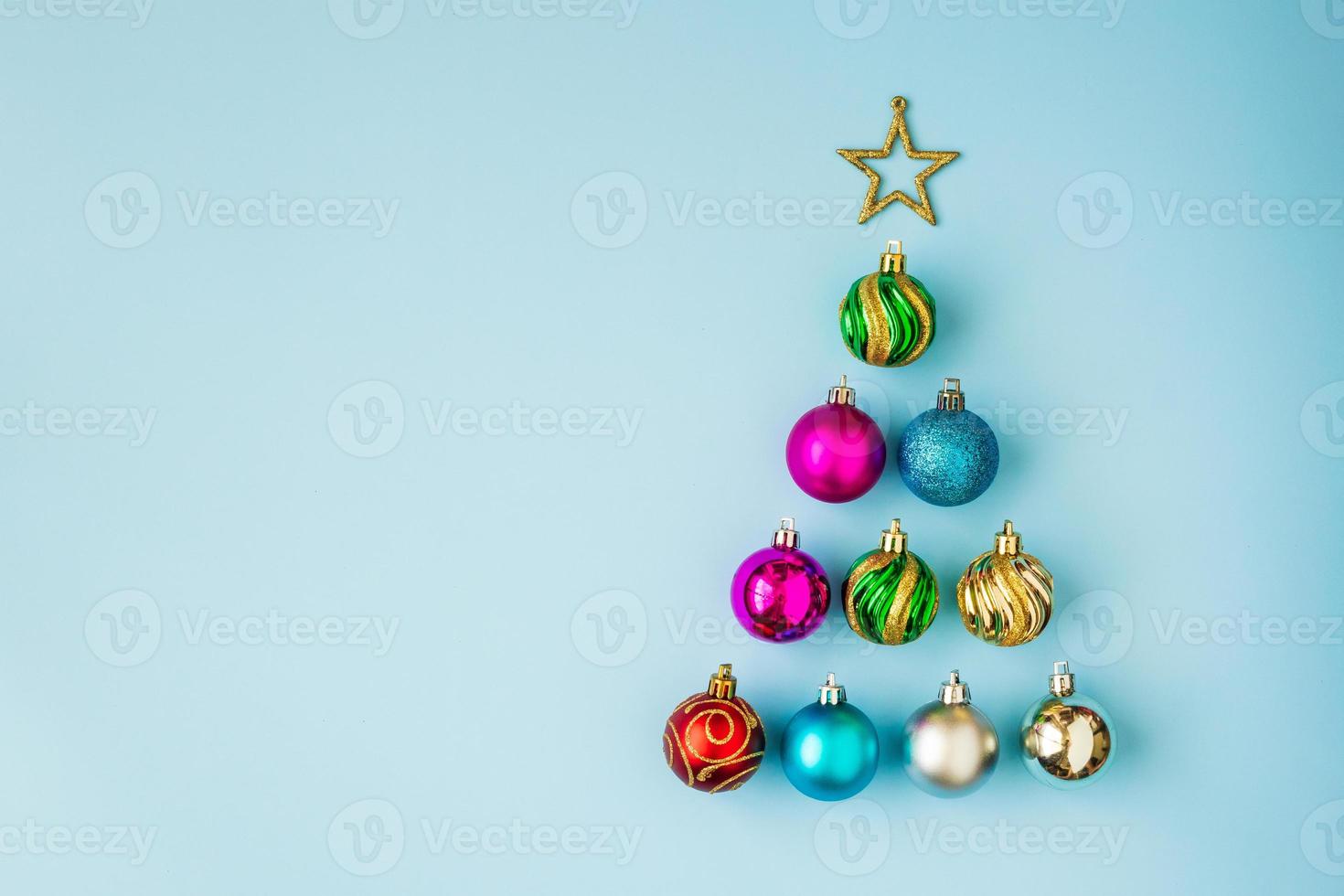 árvore de natal de enfeites e estrela dourada sobre fundo azul pastel foto