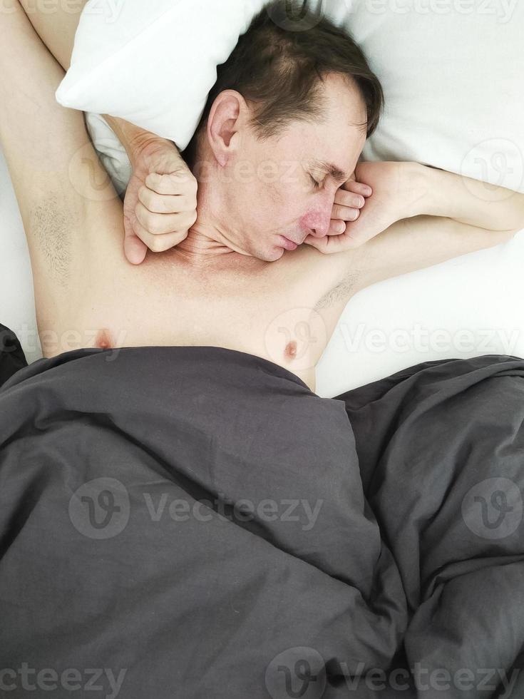 homem dormindo na cama debaixo do cobertor de manhã. foto