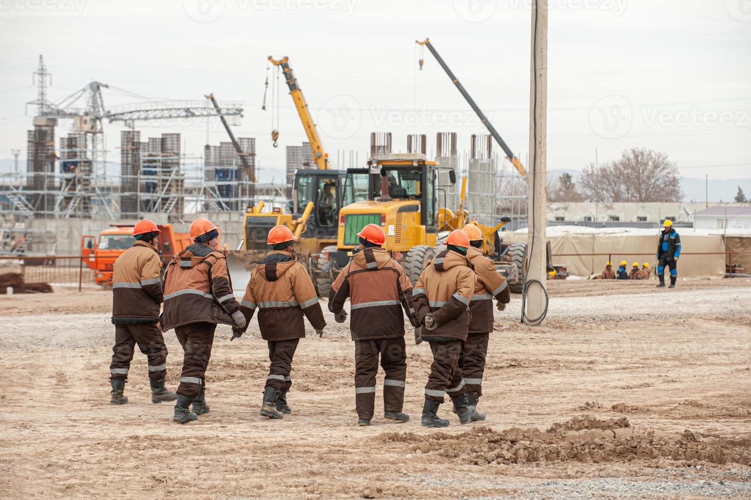 uma bela foto de trabalhadores em equipamentos especiais e capacetes com construção de petróleo e gás ao fundo