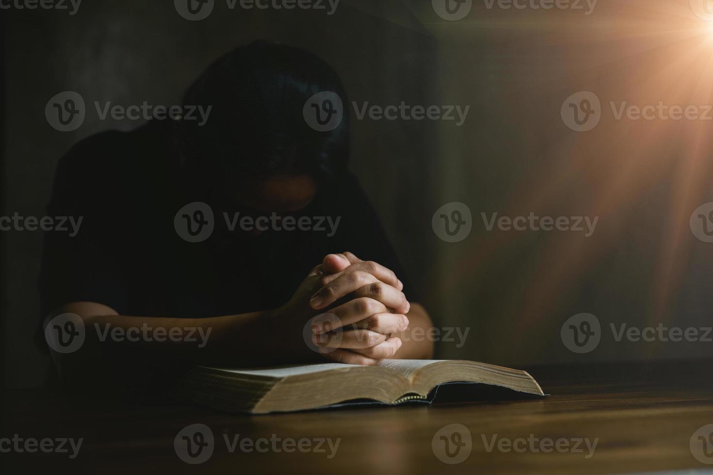 pessoa de oração mão em fundo preto. mulher católica cristã está orando a Deus no escuro na igreja. menina acreditar e fé em jesus cristo. religião de cristo e cristianismo adoram ou rezam o conceito. foto