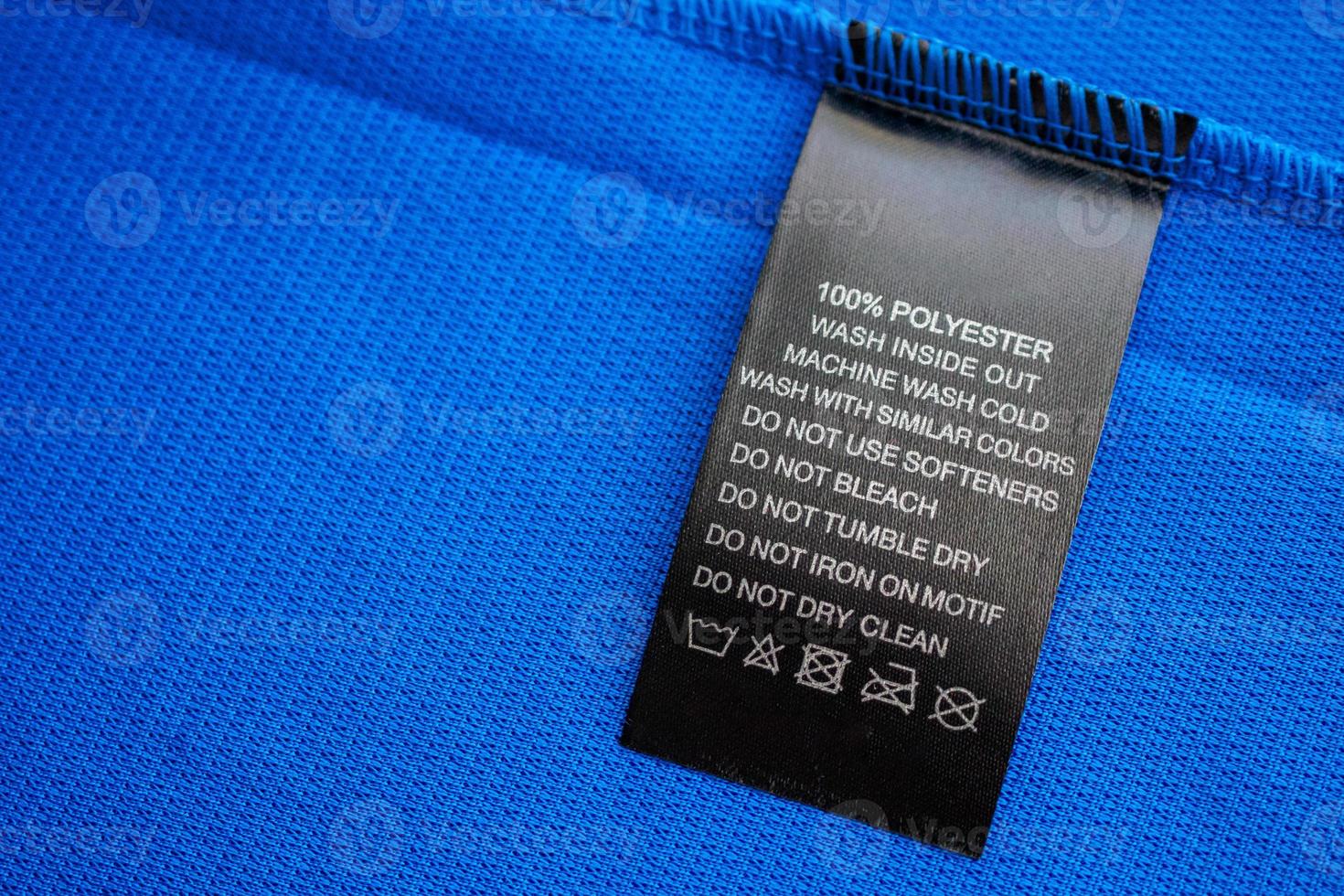 Etiqueta de roupas de instruções de lavagem de cuidados com a roupa preta na camisa esportiva de poliéster azul jersey foto