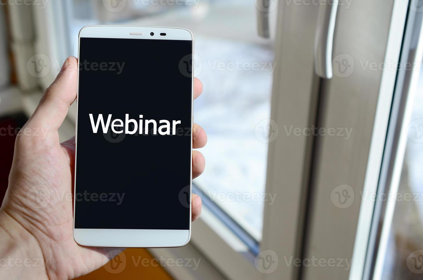 uma pessoa vê uma inscrição branca em uma tela preta de smartphone que segura na mão. webinar foto