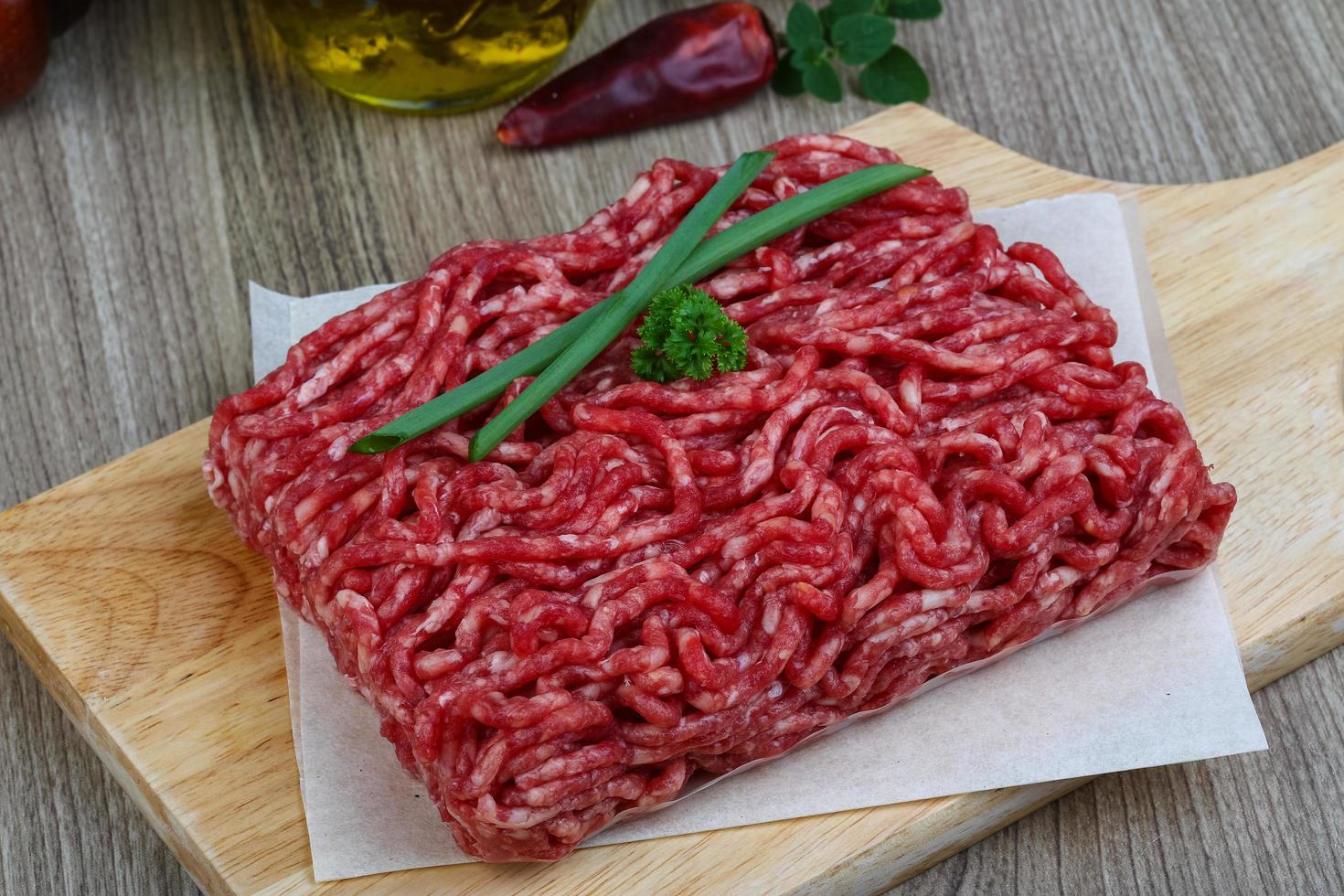 carne picada na tábua de madeira e fundo de madeira foto