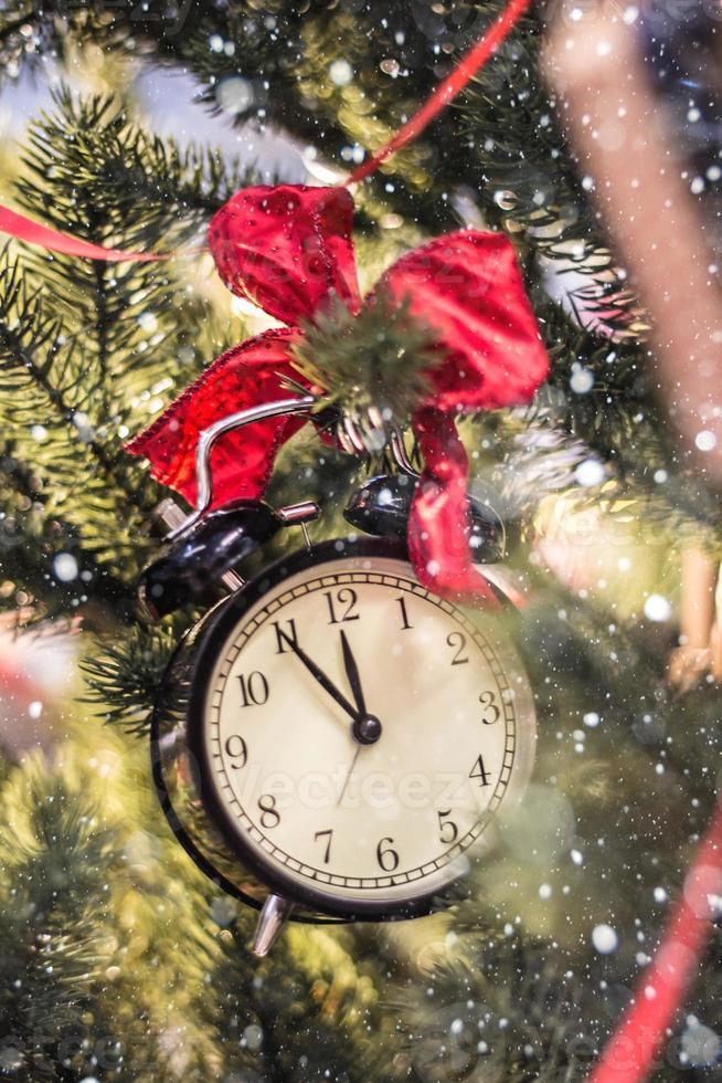 relógio de natal laço vermelho no galho de uma árvore foto