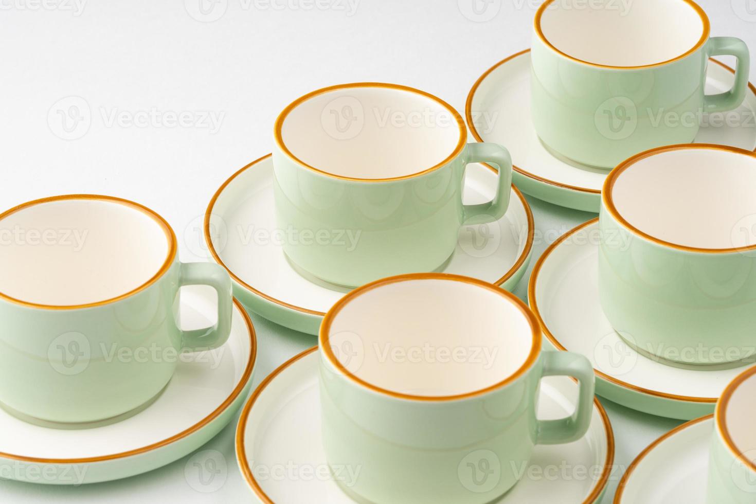 um conjunto de xícaras de cerâmica verde pastel e branco com contornos laranja foto