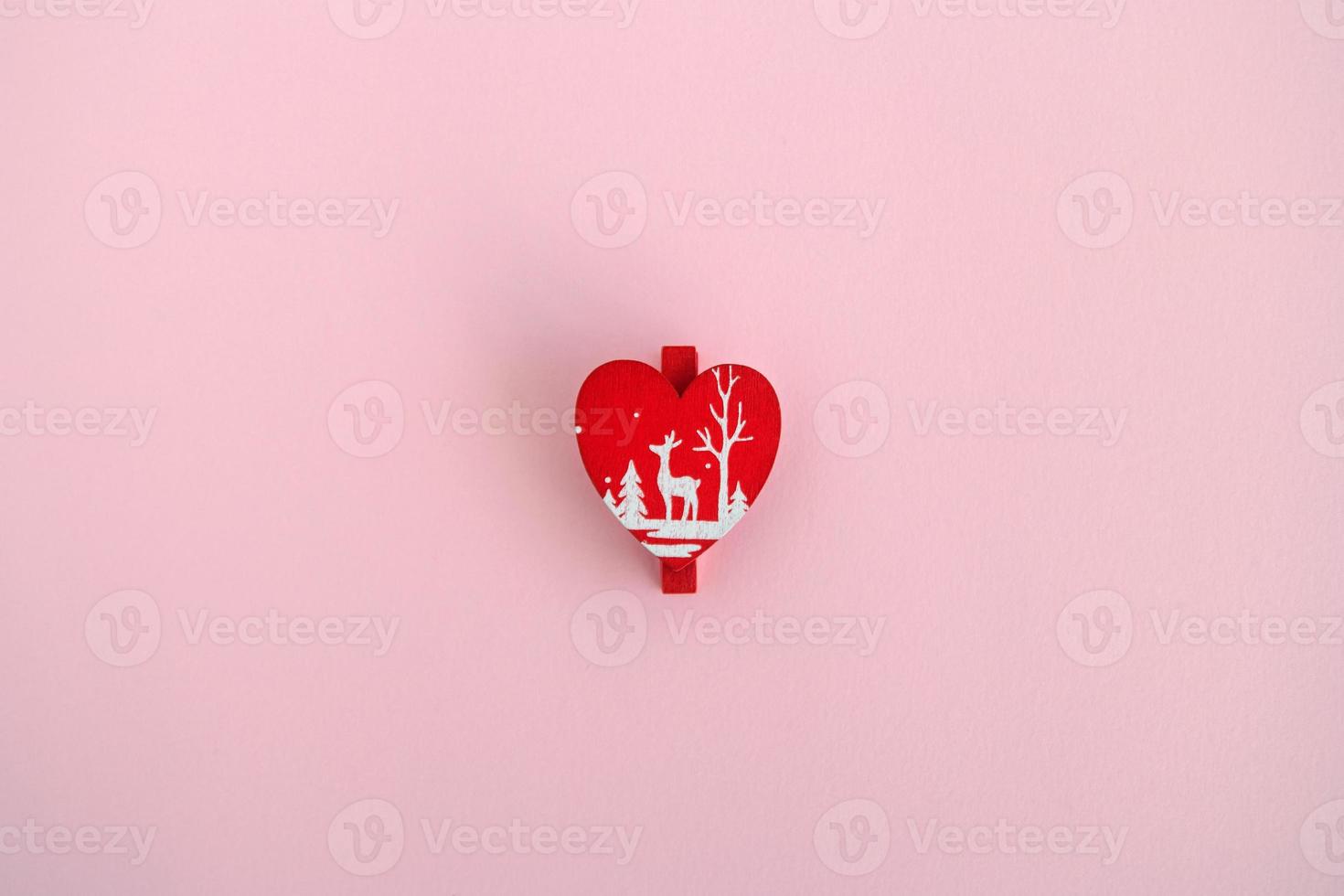 decoração de natal de madeira vermelha e ano novo em forma de coração em um fundo rosa, vista superior. foto
