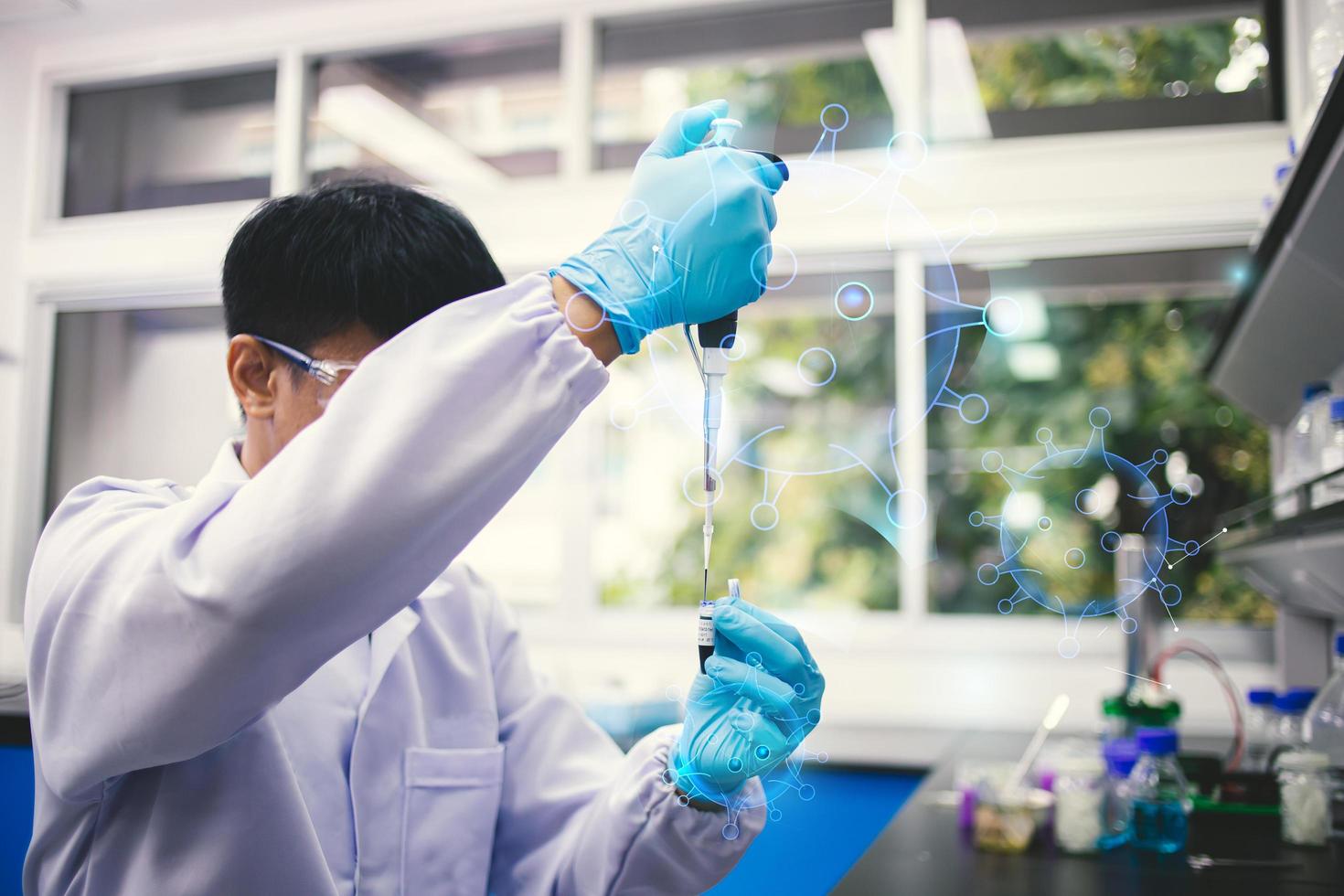 retrato de laboratório de pesquisa médica de um cientista masculino asiático em óculos usando micro pipeta para análise de teste. laboratório científico avançado para medicina, biotecnologia, desenvolvimento de microbiologia foto