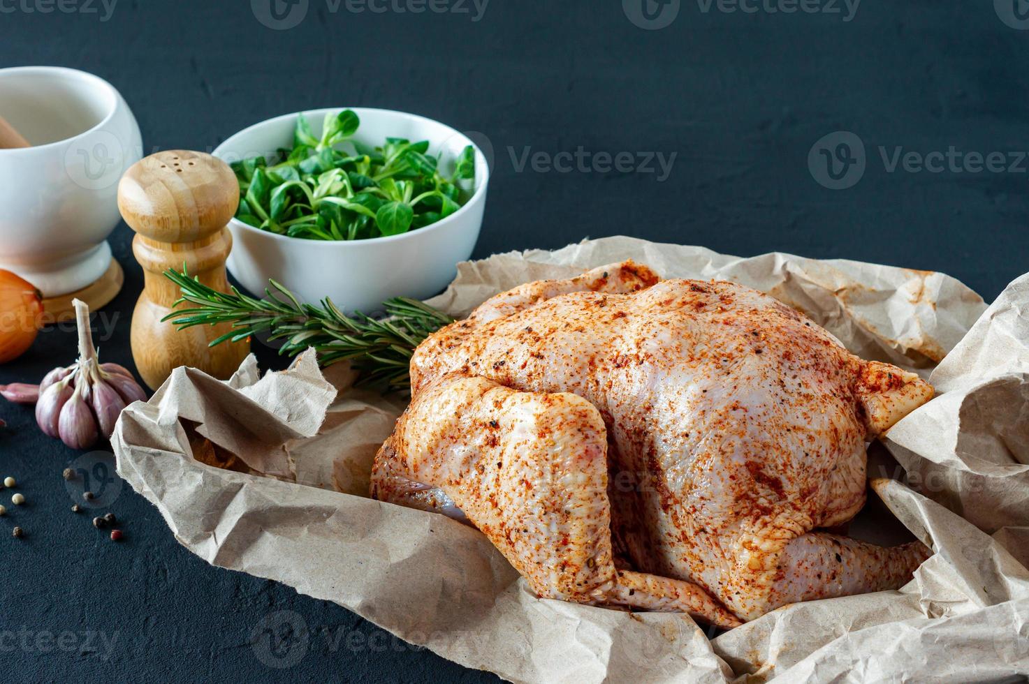 frango cru fresco em papel manteiga e especiarias para cozinhar foto