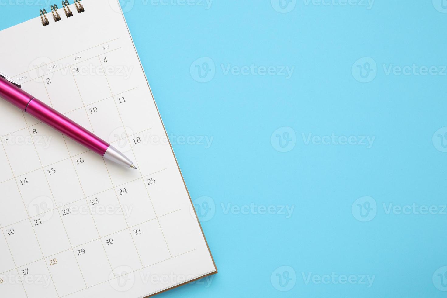 página do calendário com caneta close-up no conceito de reunião de compromisso de planejamento de negócios de fundo azul foto