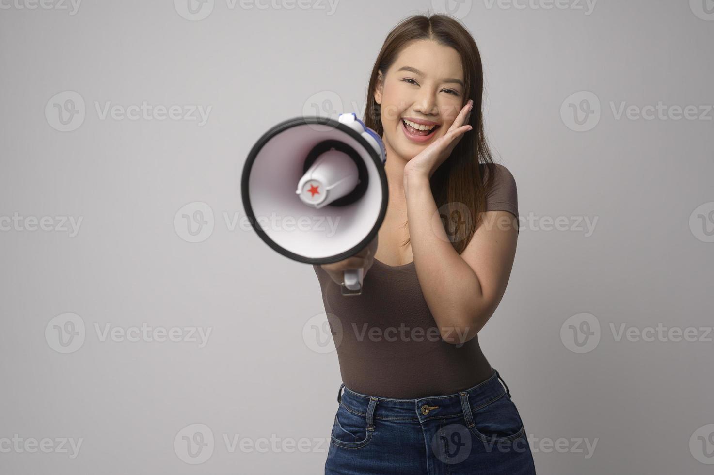 jovem sorridente segurando o megafone sobre o estúdio de fundo branco. foto