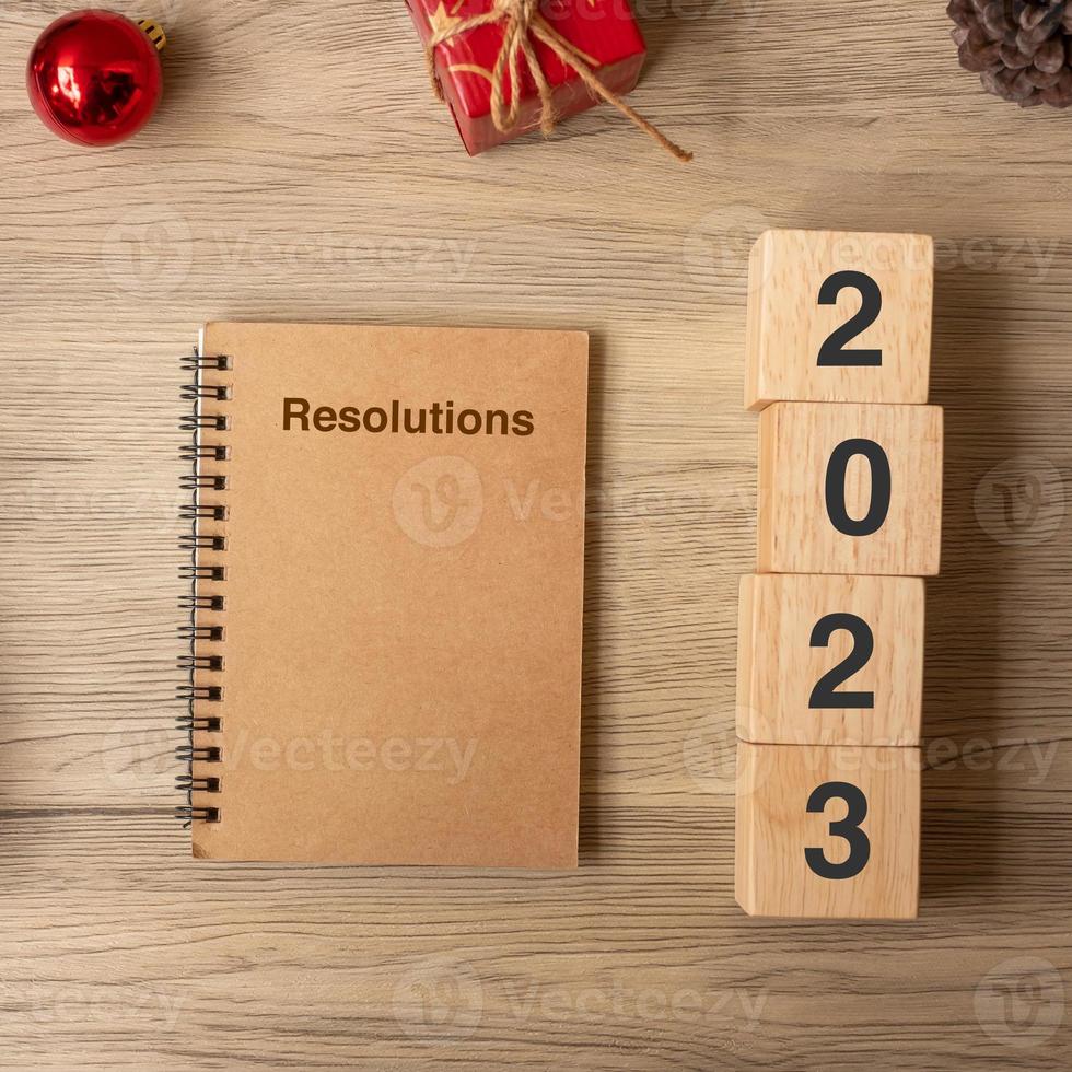 2023 ano novo com notebook, presente de natal e caneta na mesa de madeira. natal, feliz ano novo, objetivos, resolução, lista de tarefas, início, estratégia e conceito de plano foto