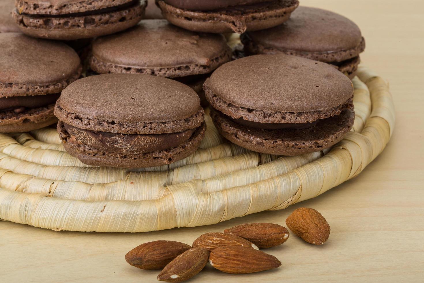 macaroons de chocolate na placa de madeira e fundo de madeira foto