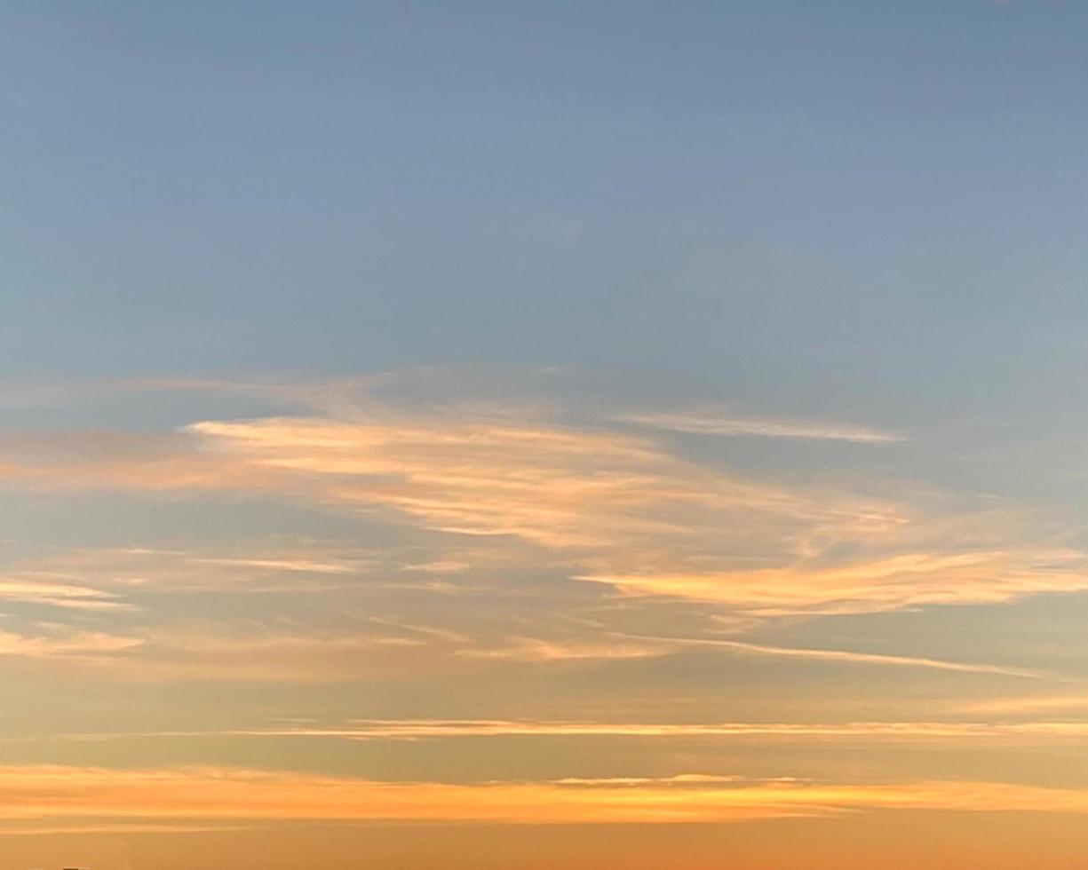 amanhecer o céu é azul e as nuvens listradas são iluminadas pelo sol amarelo. foto