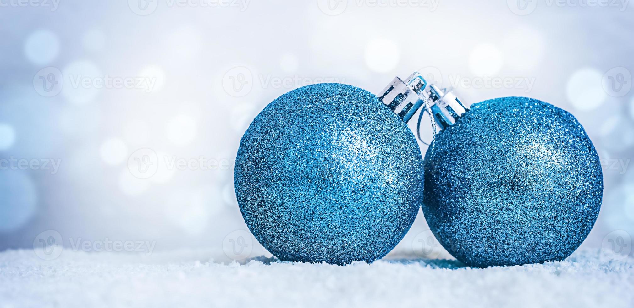 duas decorações de natal azuis na neve em um fundo azul desfocado com bokeh e espaço de cópia. foto