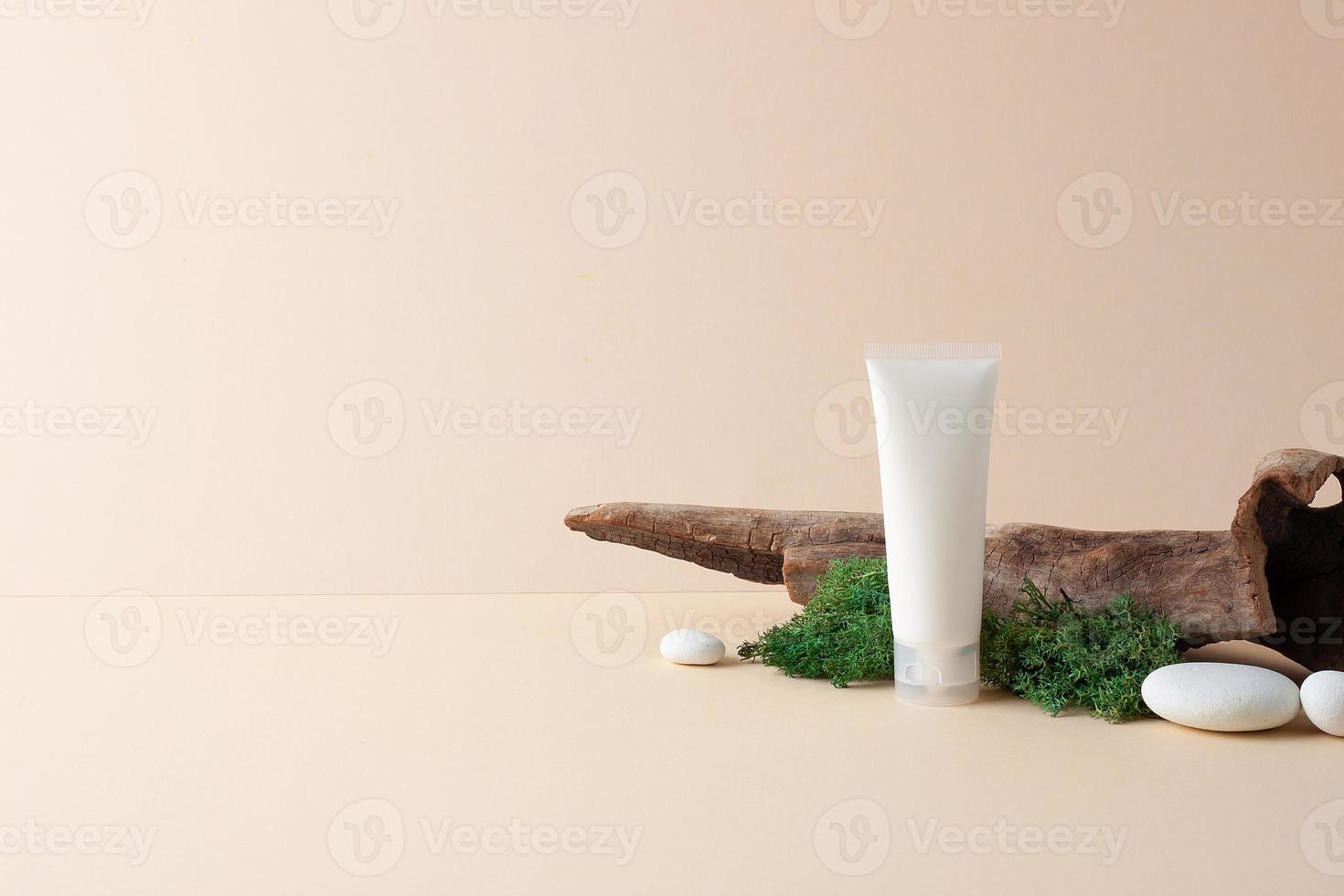 tubo branco de creme cosmético com madeira e musgo em fundo pastel. feche, copie o espaço. foto