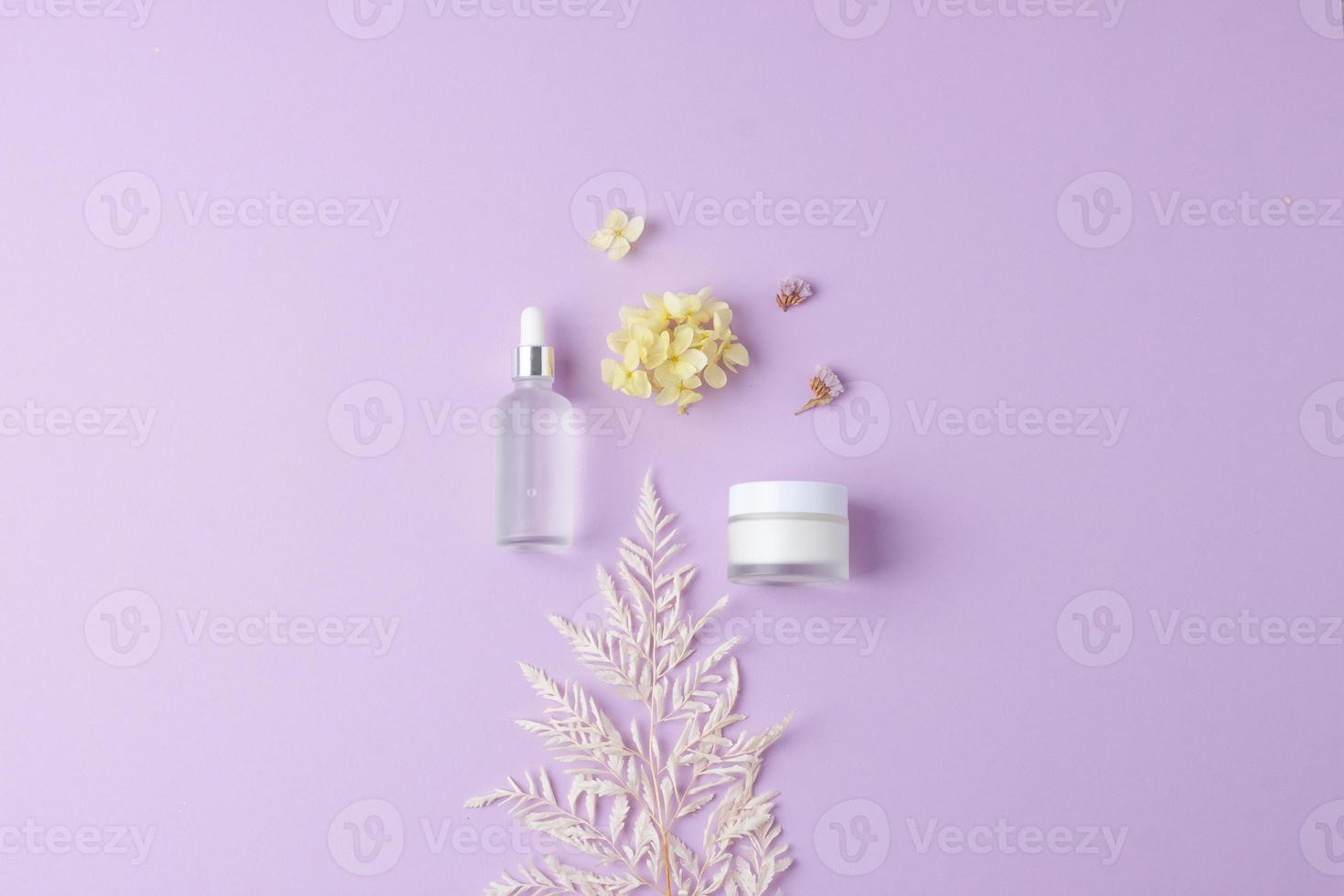 produtos cosméticos para cuidados com a pele com flores em fundo rosa. postura plana, copie o espaço foto
