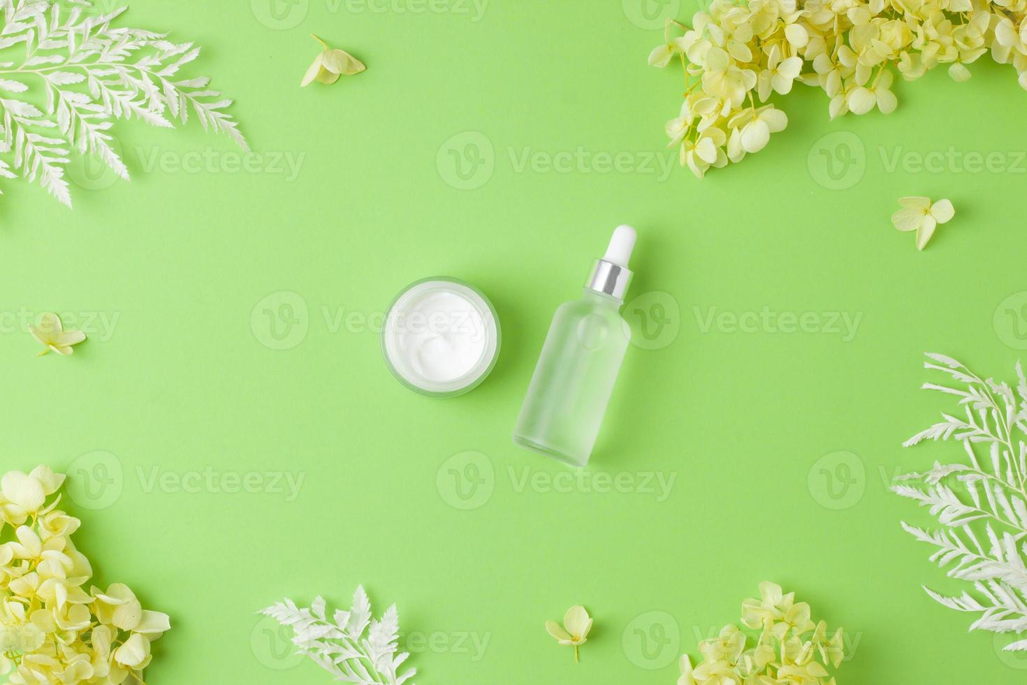 produtos cosméticos para cuidados com a pele com flores sobre fundo verde. postura plana foto