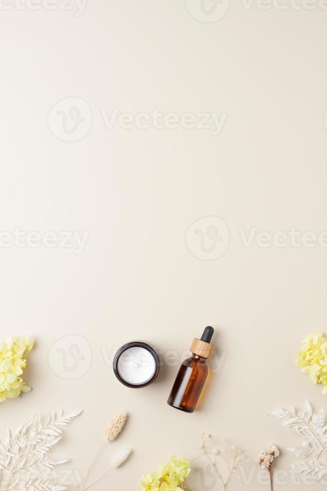 produtos cosméticos para cuidados com a pele com flores em fundo bege pastel. postura plana, copie o espaço foto