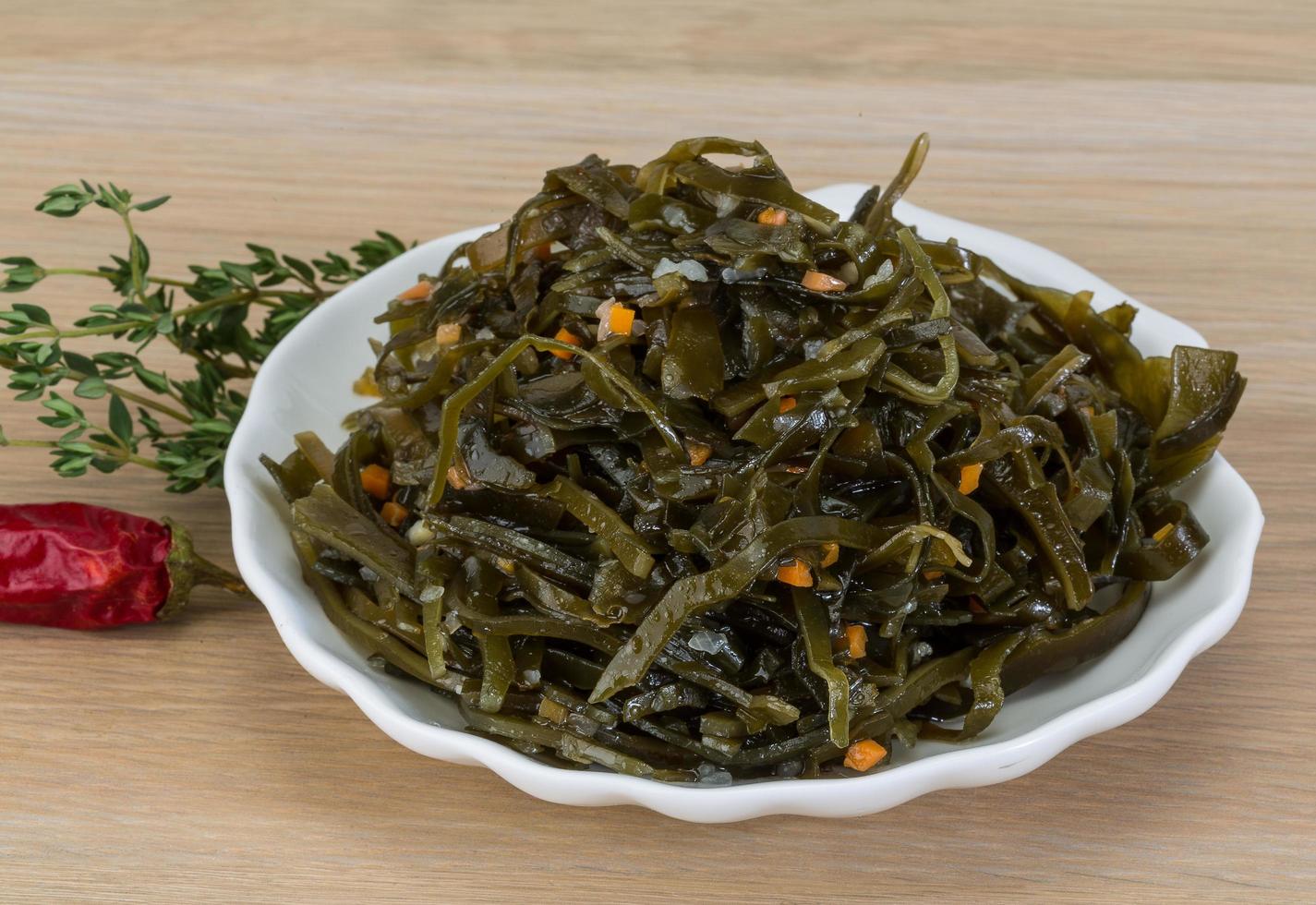 salada de laminaria em uma tigela com fundo de madeira foto